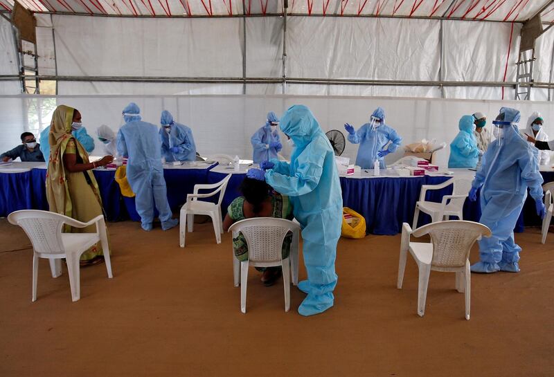 A healthcare worker takes a swab from a woman for a rapid antigen test at a check-up point in Ahmedabad, India. Reuters