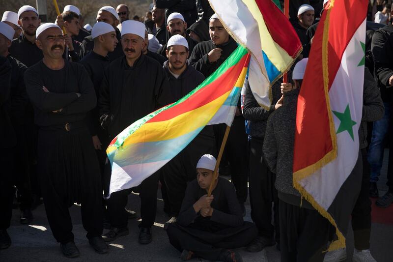 epa07130757 Members of the Druze community hold Syrian and Druze flags as they protest outside an Israeli polling center during local elections in the Druze village of Majdal Shams, in the Golan Heights, 30 October 2018. Hundreds of the Druze community gathered outside an Israeli polling center, set for the first since Israel captured Golan Heights from Syria in the 1967 war, to protest against holding the elections in their village that would allow about 12 percent of the Druze community who hold Israeli citizenship to vote in the Israeli local elections.  EPA/ATEF SAFADI