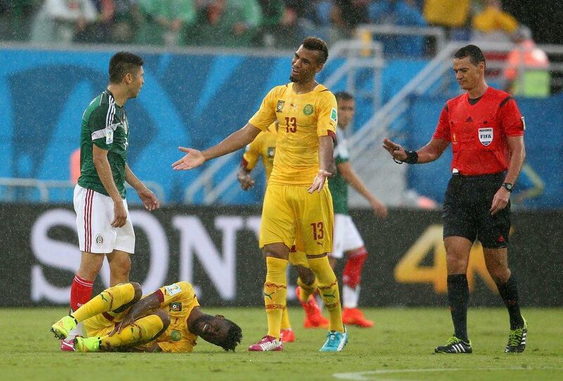 Referee Wilmar Roldan, right, gestures to Oribe Peralta of Mexico, left, as Alex Song of Cameroon lies on the ground during their 2014 World Cup Group A match on Friday. Julian Finney / Getty Images