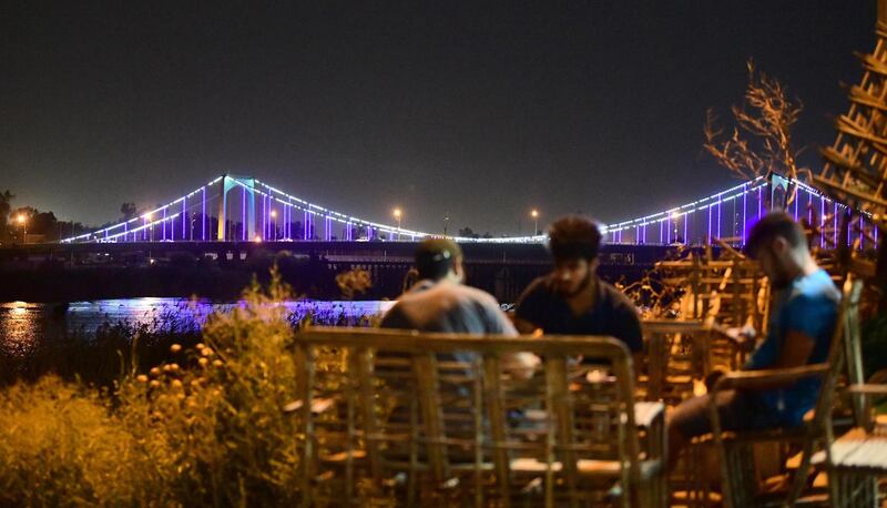 The suspension bridge in the Green Zone is seen in the background as Iraqi men sit in a cafe next to the Tigris.   EPA
