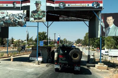 A Russian convoy drives through a checkpoint decorated with portraits of Syrian President Bashar al-Assad in the central city of Hama, on August 15, 2018. (Photo by Andrey BORODULIN / AFP)