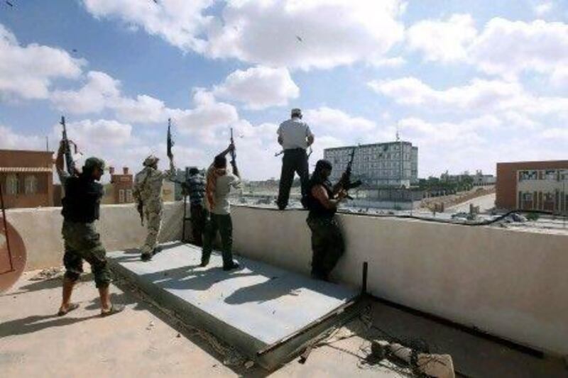 Libyan militia fighters aligned with the defence ministry celebrate on top of a building in the centre of the former Qaddafi stronghold of Bani Walid.
