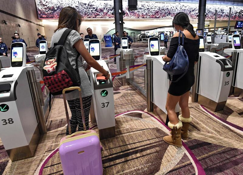 Passengers scan their passports at automated immigration gates at the newly-opened Changi International Airport's Terminal 4 in Singapore on October 31, 2017. 
Singapore's newly-opened automated Changi International airport Terminal 4 began full operations on October 31. The cutting edge terminal, which is half the size of Terminal 3 at 225,000 square meters, makes it Changi Airport's smallest terminal. / AFP PHOTO / ROSLAN RAHMAN