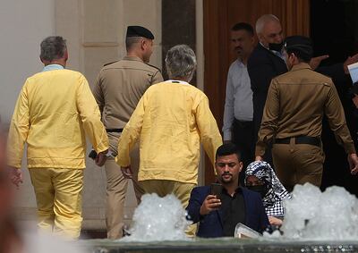 Jim Fitton, right, and Volker Waldman are handcuffed outside a courtroom in Baghdad, Iraq, on Monday. AP