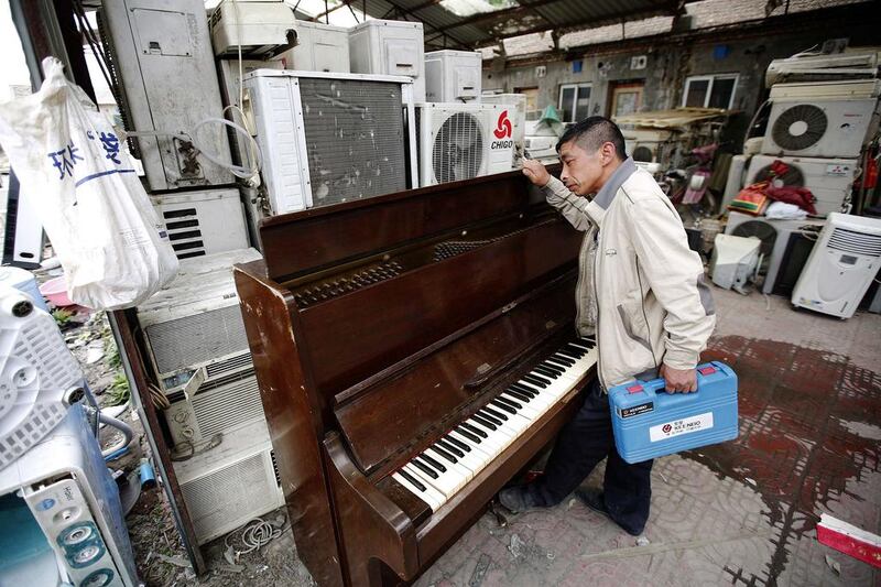 A recycling worker looks at a broken piano in the yard of a tenement house at Dongxiaokou village. Kim Kyung-Hoon / Reuters