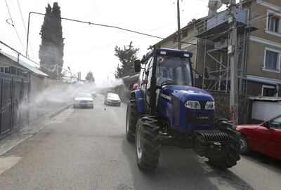 A tractor driven by a worker wearing a protective suit sprays disinfectant on the street to prevent the spread of coronavirus disease (COVID-19), in Marneuli near Tbilisi, Georgia March 25, 2020. REUTERS/Irakli Gedenidze