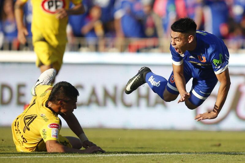 Universidad de Chile’s Felipe Mora, right, falls down after a tackle from San Luis’ Daniel Vicencio during a Chilean Clausura football match in Santiago.  Elvis Gonzalez / EPA