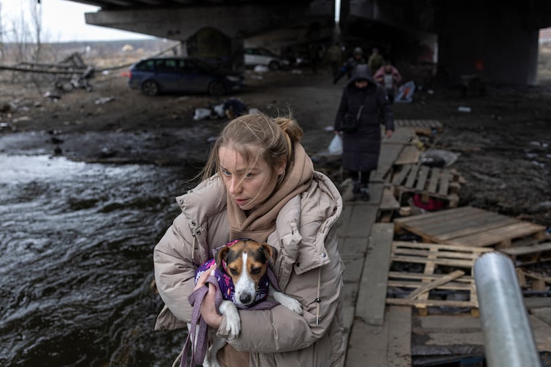 A woman carries her dog during an evacuation in Irpin. Reuters