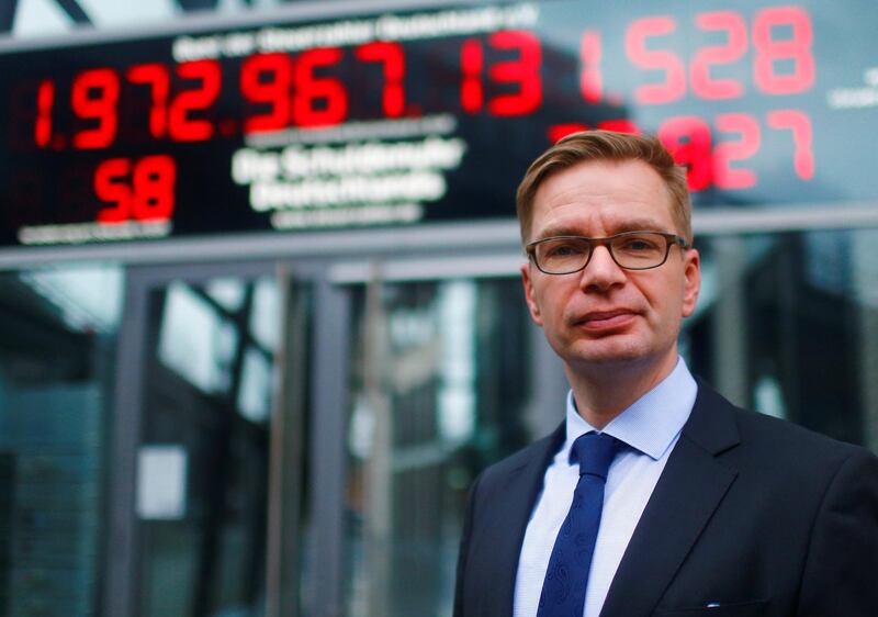 President of the German Taxpayers Association (Bund der Steuerzahler) Reiner Holznagel stands in front of the so-called debt clock (Schuldenuhr), which will run backwards for the first time in its 22-year existence, in Berlin, Germany December 22, 2017. REUTERS/Hannibal Hanschke