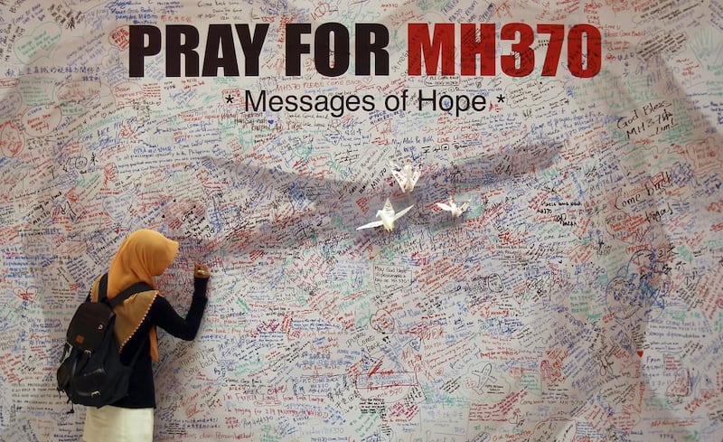 A woman writes a message for passengers aboard a missing Malaysia Airlines plane. Investigators have concluded that one or more people with significant flying experience hijacked the missing Malaysia Airlines jet. Lai Seng Sin / AP