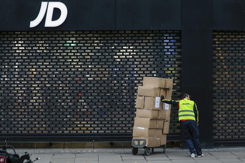 A delivery courier waits with a trolley of boxes outside a closed JD Sports Fashion Plc store on Oxford Street in central London, U.K., on Monday, Nov. 30, 2020. Philip Green's Arcadia Group is poised to seek protection from creditors and become the most notable U.K. retail insolvency since the beginning of the coronavirus pandemic. Photographer: Jason Alden/Bloomberg