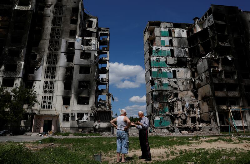 Residents chat in front of a destroyed building in Borodianka, as Russia's attacks on Ukraine continue. Reuters