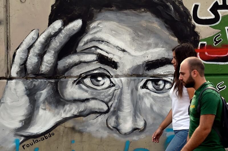 Protesters pass by a wall with graffiti during ongoing anti-government in Beirut, Lebanon.  EPA