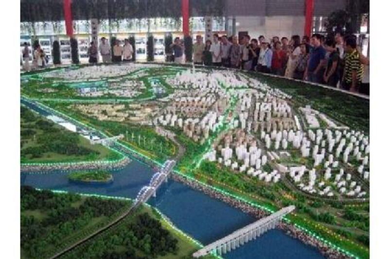 Visitors look at a model of the eco-city under construction near the port city of Tianjin.