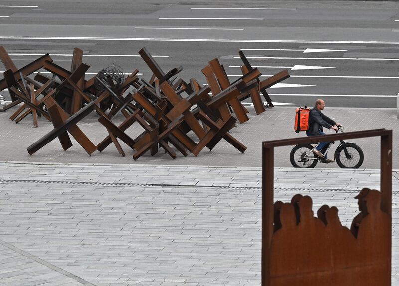 A delivery service employee rides a bicycle past anti-tank hedgehogs in the center of the Ukrainian capital Kyiv. AFP