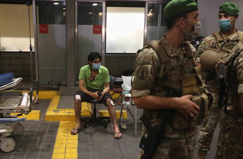 An injured man sits outside American University of Beirut medical centre on August 5, 2020. Reuters