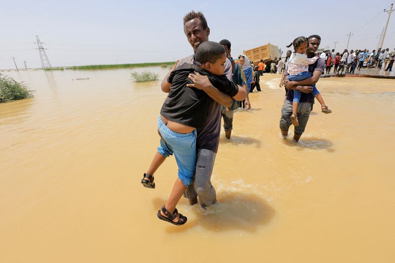 Residents of Al Jazeera state south of the Sudanese capital Khartoum wade through flood water in late August. Reuters