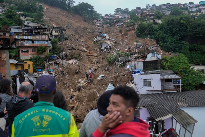 People wait as rescue workers and volunteers search for survivors in an area affected by landslides in Petropolis, Brazil. AP