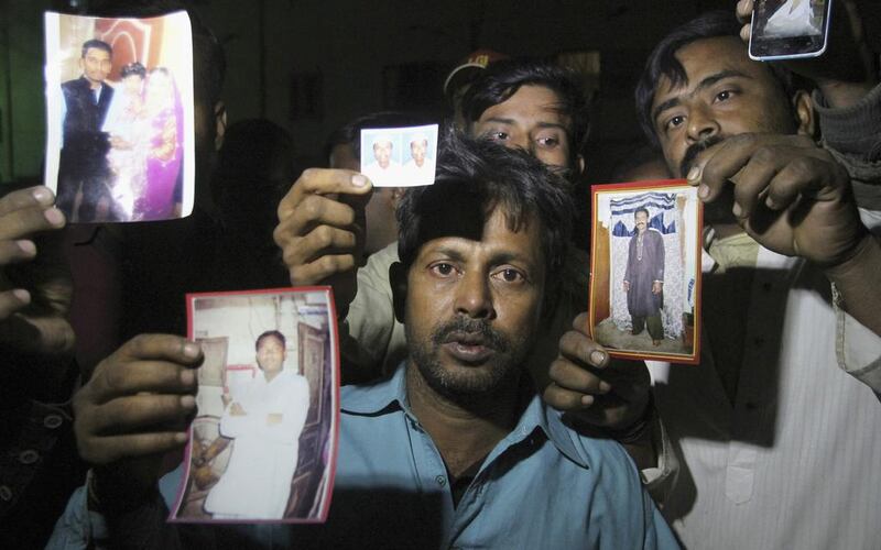 Pakistanis show pictures of missing family members. Fareed Khan / AP Photo