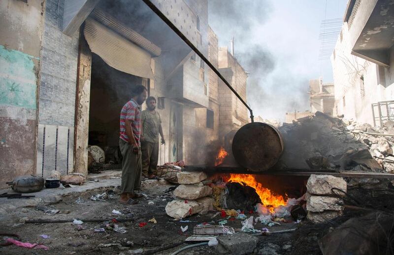 Syrians Mohammed Ibrahim, left, and Abu Majd distill melted plastic in a barrel as part of a refining process to produce fuel in Aleppo’s rebel-held eastern district of Sakhur on September 10, 2016, days before Abu Mahjd and another colleague were burned to death when a barrel exploded during the melting process. Karam Al Masri/ AFP