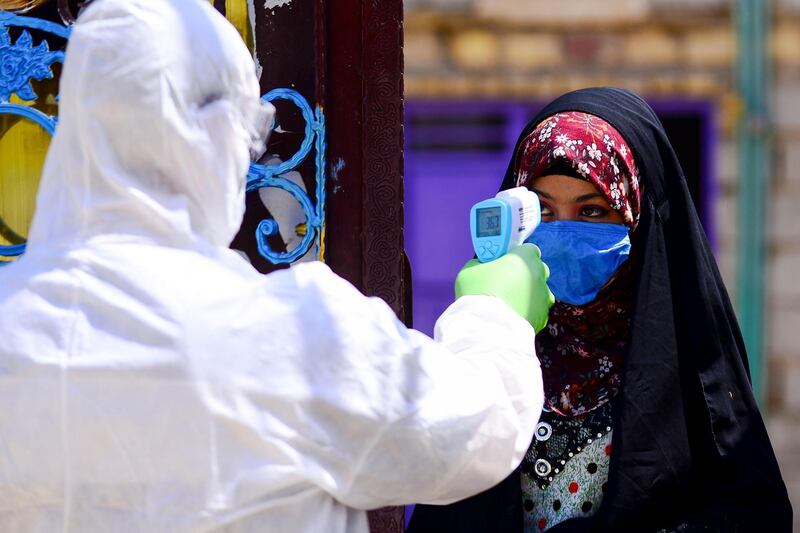 An Iraqi medic takes the temperature of a woman in Iraq's central shrine city of Najaf, during the nationwide lockdown to stem the spread of the novel coronavirus.   AFP