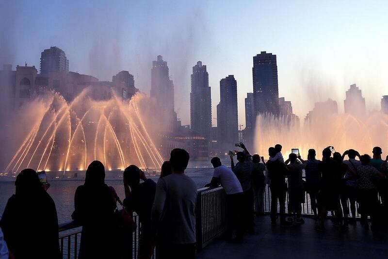 Tourists take photos of the fountain at the Burj Khalifa lake in Dubai. The travel and tourism sector continued to expand in May. Satish Kumar / The National
