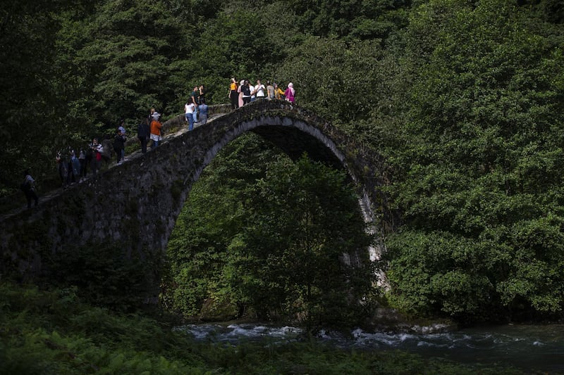 People walk on a bridge in the Camlihemsin district of Rize, Turkey. Turkish authorities have now allowed the reopening of restaurants, cafes, parks and beaches, as well as lifting the ban on inter-city travel, as the country eases the restrictions it had imposed in a bid to stem the spread of COVID-19.  EPA