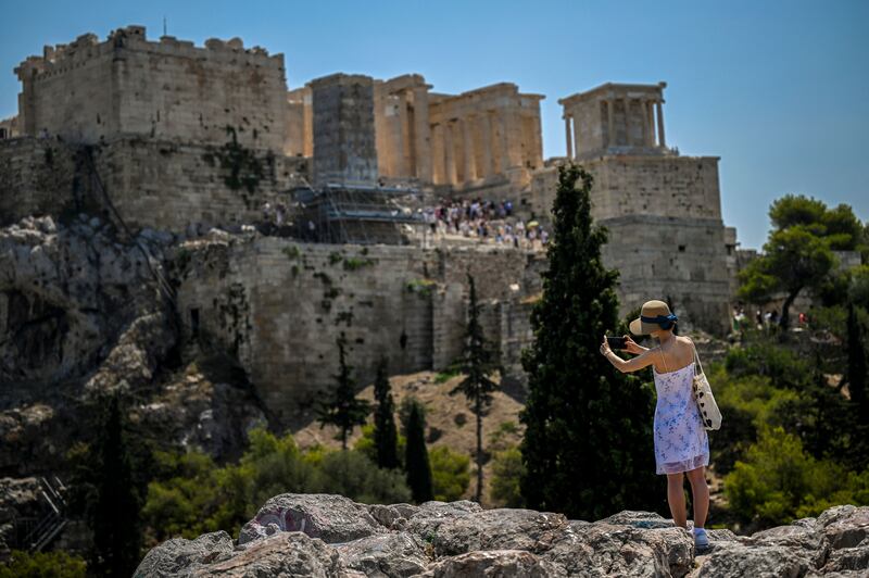 A woman takes a photograph of the Acropolis in Athens in high temperatures. AFP