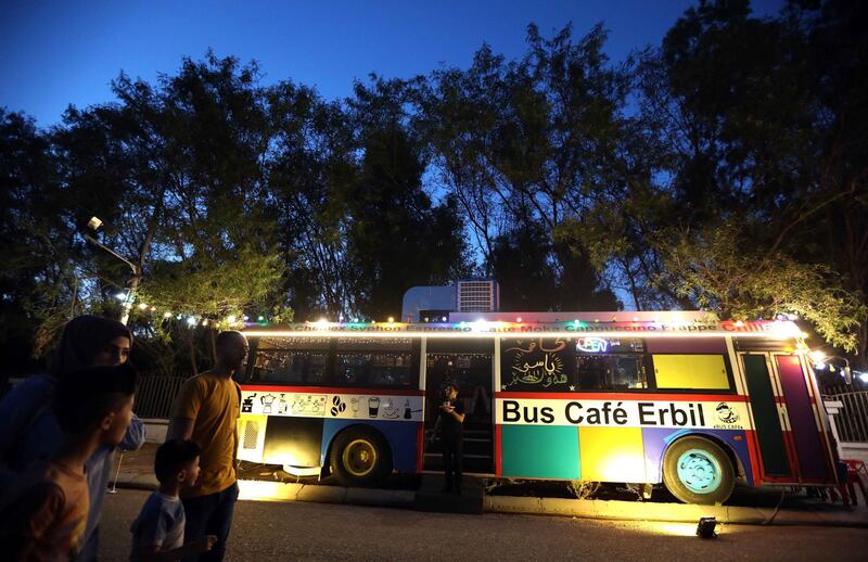 Pedestrians walk past "The Bus Cafe Erbil" in Erbil, the capital of Iraq's Kurdish autonomous region late on the long weekend of the Eid al-Fitr holiday.  AFP