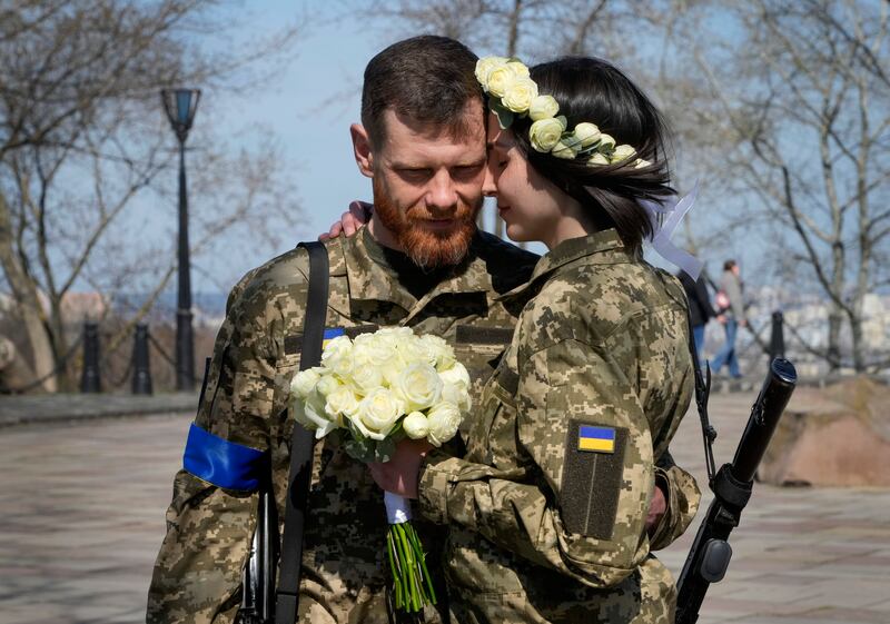 Ukrainian soldiers Anastasia and Vyacheslav embrace prior to their wedding ceremony in a city park in Kyiv, Ukraine. AP