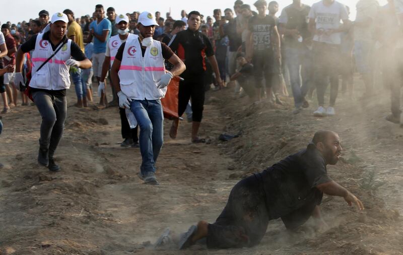 Medics and protesters run to evacuate wounded man during a protest east of Gaza City, Friday, Aug. 31, 2018. Gaza's Health Ministry says Israeli gunfire wounded about 80 Palestinians at a weekly protest along the border with Israel. (AP Photo/Adel Hana)
