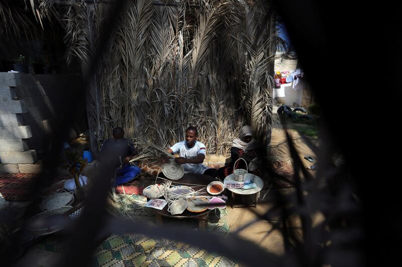 Members of a Palestinian family make traditional decorative objects with palm tree leaves to be sold in the local market, in the central Gaza Strip.  Reuters