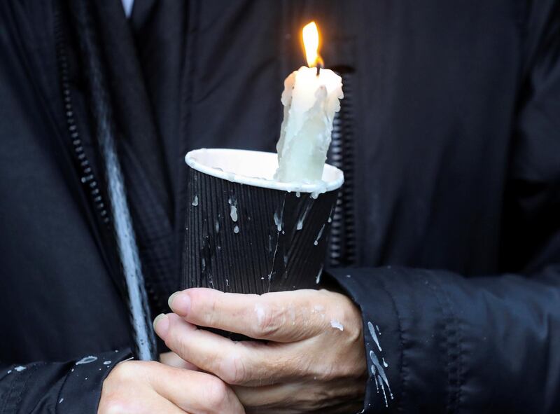 A mourner waiting for the funeral procession of John Hume holds a candle outside St Eugene's Cathedral. Reuters
