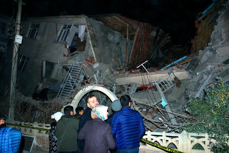 People look at a collapsed building in Elazig city centre in the eastern Turkey on Friday AP