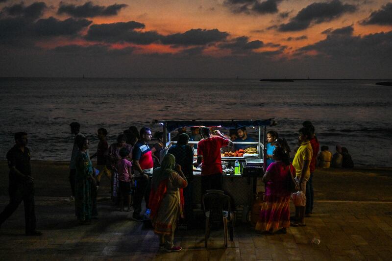 Visitors buy street food from a vendor selling prawns and crabs from a cart at the Galle Face promenade in Colombo.  AFP