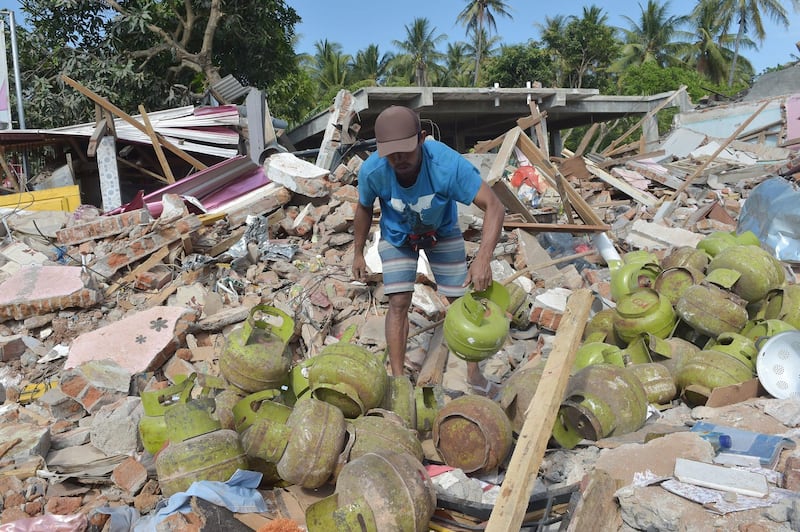 A man salvages cooking gas cylinders from the ruins of a shop belonging to his brother-in-law in Pemenang, northern Lombok.  AFP