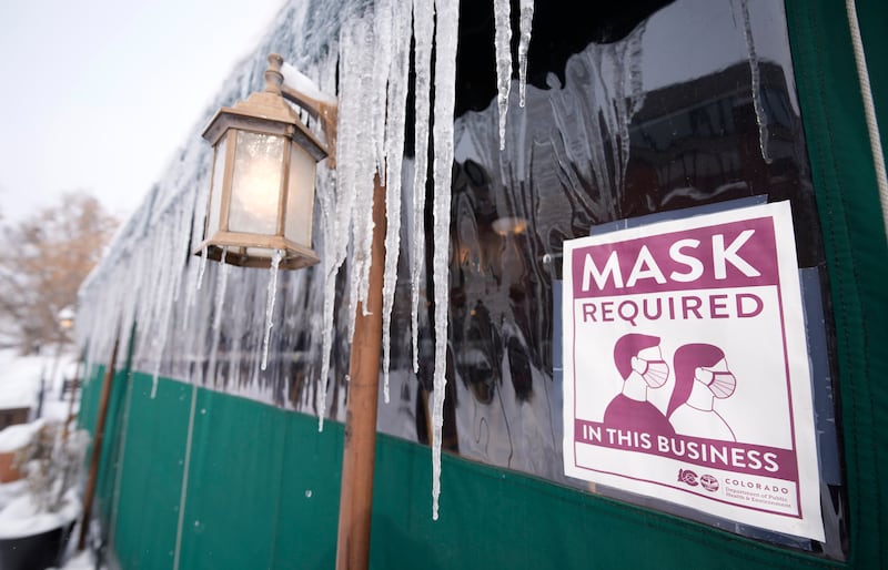 A sign advises patrons of a Covid-19 restriction while long icicles grow from an awning outside a restaurant in Denver, Colorado. AP