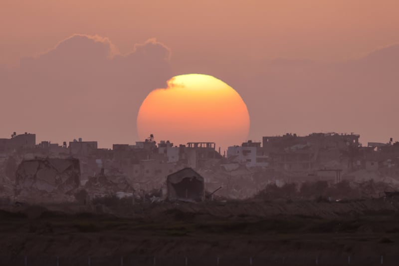 The sun sets behind destroyed buildings in Gaza. AFP