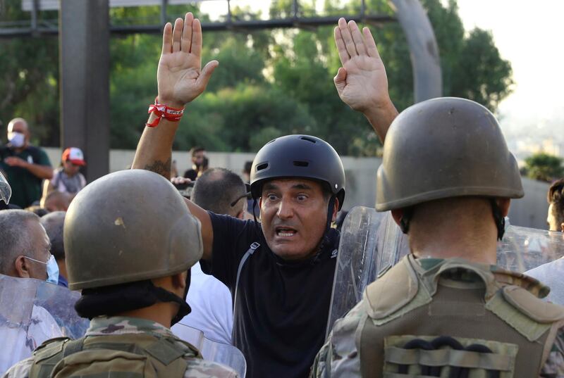 An anti-government protester reacts in front of Lebanese soldiers, during a protest against the Lebanese President Michel Aoun near the presidential palace, in Baabda east of Beirut. AP