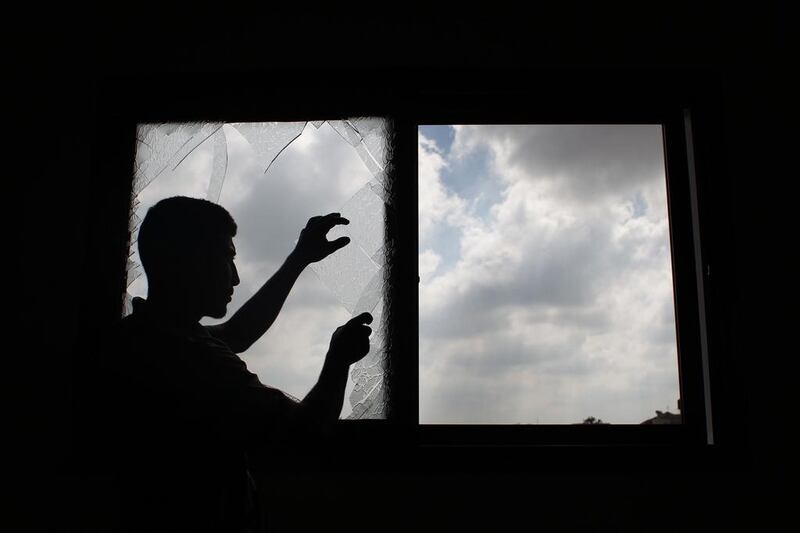 A Palestinian man removes shattered glass from a window following an Israeli air strike in Khan Yunis, in the central Gaza Strip, on June 25, 2014. Said Khatib/AFP Photo