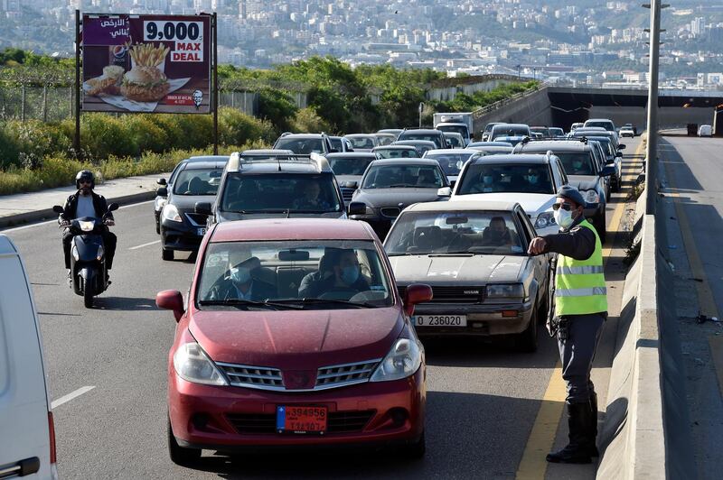 epa08353223 Lebanese policemen check vehicles license plates at a highway checkpoint in Ouzai area south of Beirut, Lebanon, 09 April 2020. Checkpoints were set up to implementing strict measures that allow vehicles with even or odd plate numbers to drive for three days a week each and Sundays will be banned for all vehicles as a part to stem the spread of the ongoing coronavirus Covid-19 pandemic.  EPA/WAEL HAMZEH