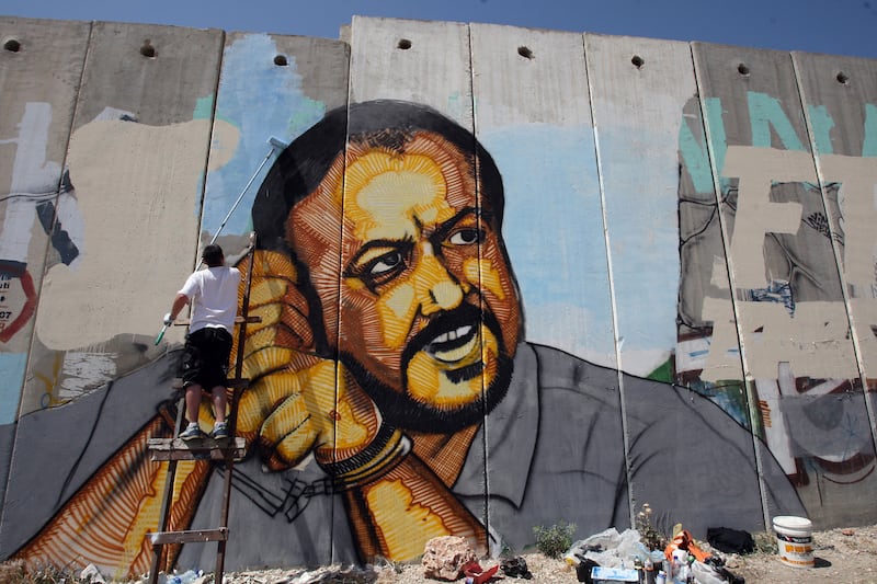 A Palestinian artist finishes a portrait of Barghouti on a cement barrier near the Israeli-controlled Qalandia checkpoint between Jerusalem and Ramallah in 2010. AFP 