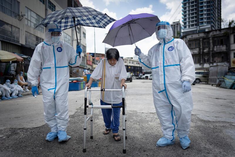 Health officials escort an elderly women back home  after she had a coronavirus test at a wet market in Kuala Lumpur, Malaysia. AP Photo
