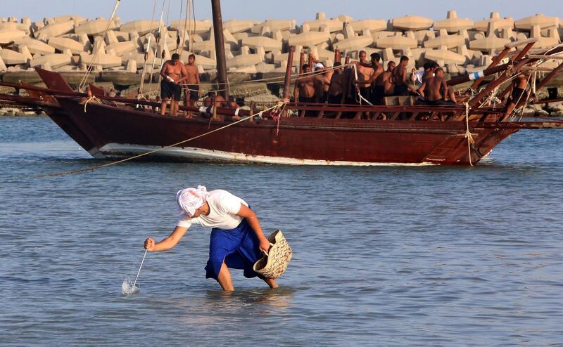 A pearl diver uses a gig to hunt for fish in the waters near a dhow in Kuwait City. AFP