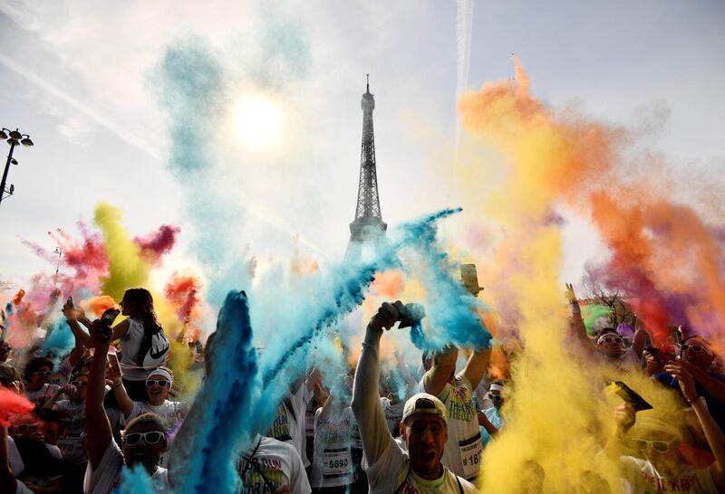 People celebrate at the end of the Colour Run 2018 race in front of the Eiffel Tower in Paris. Christophe Simon / AFP