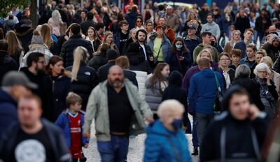 People, some wearing face masks, walk along a busy shopping street in the centre of Liverpool. Reuters