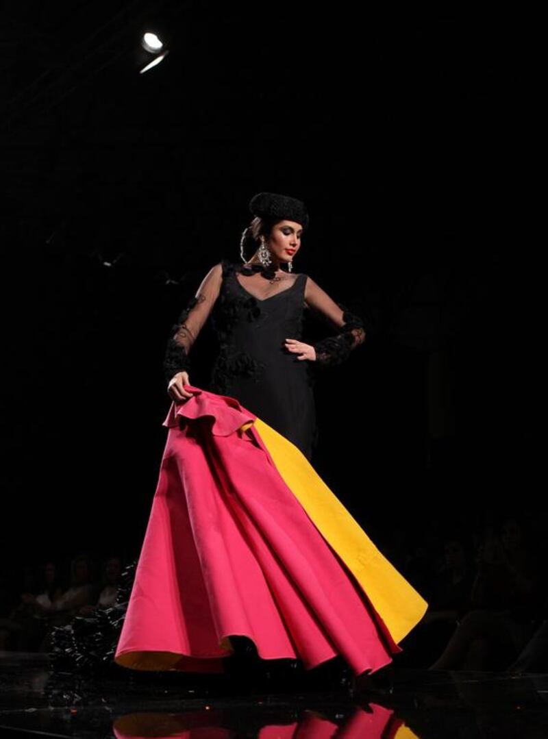 A model with a muleta and a "montera" (Matador's hat) presents a creation by Molina Moda Flamenca. AFP