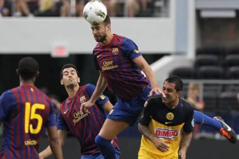 ARLINGTON, TX - AUGUST 06: Gerard Pique #3 of FC Barcelona heads the ball against Daniel Montenegro #10 of Club America at Cowboys Stadium on August 6, 2011 in Arlington, Texas.   Ronald Martinez/Getty Images/AFP== FOR NEWSPAPERS, INTERNET, TELCOS & TELEVISION USE ONLY ==
 *** Local Caption ***  565098-01-09.jpg