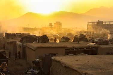 An Afghan woman who was displaced from volatile areas works on the top of her house roof in temporary shelters, on December 17, 2020. EPA