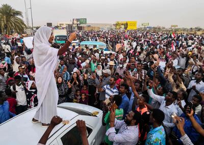 TOPSHOT - Alaa Salah, a Sudanese woman propelled to internet fame earlier this week after clips went viral of her leading powerful protest chants against President Omar al-Bashir, addresses protesters during a demonstration in front of the military headquarters in the capital Khartoum on April 10, 2019. In the clips and photos, the elegant Salah stands atop a car wearing a long white headscarf and skirt as she sings and works the crowd, her golden full-moon earings reflecting light from the fading sunset and a sea of camera phones surrounding her. Dubbed online as "Kandaka", or Nubian queen, she has become a symbol of the protests which she says have traditionally had a female backbone in Sudan.
 / AFP / -
